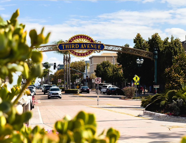 A busy street in Chula Vista with cars driving along, showcasing urban life and transportation.