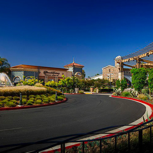 A shopping center at Otay Ranch Chula Vista featuring a central fountain surrounded by retail spaces and greenery.