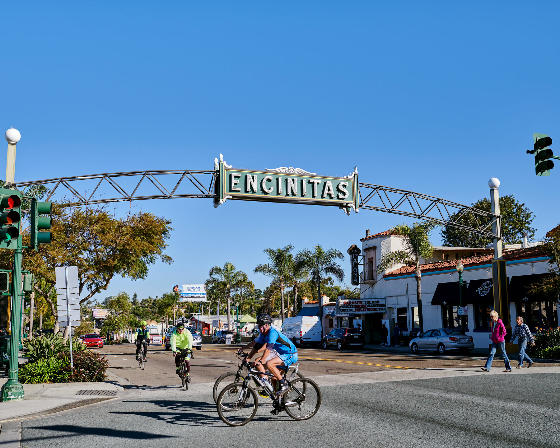 A man cycling through an archway in Encinitas, California, surrounded by vibrant scenery and sunlight.