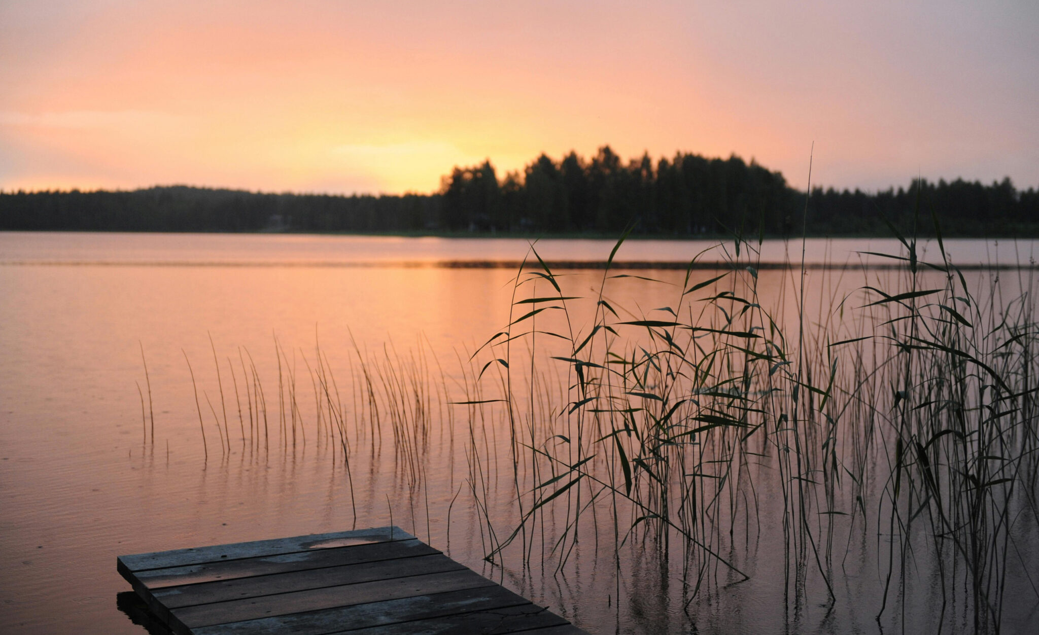 A serene wooden dock extends into a lake at sunset, casting reflections of vibrant colors, Lakeside, CA.