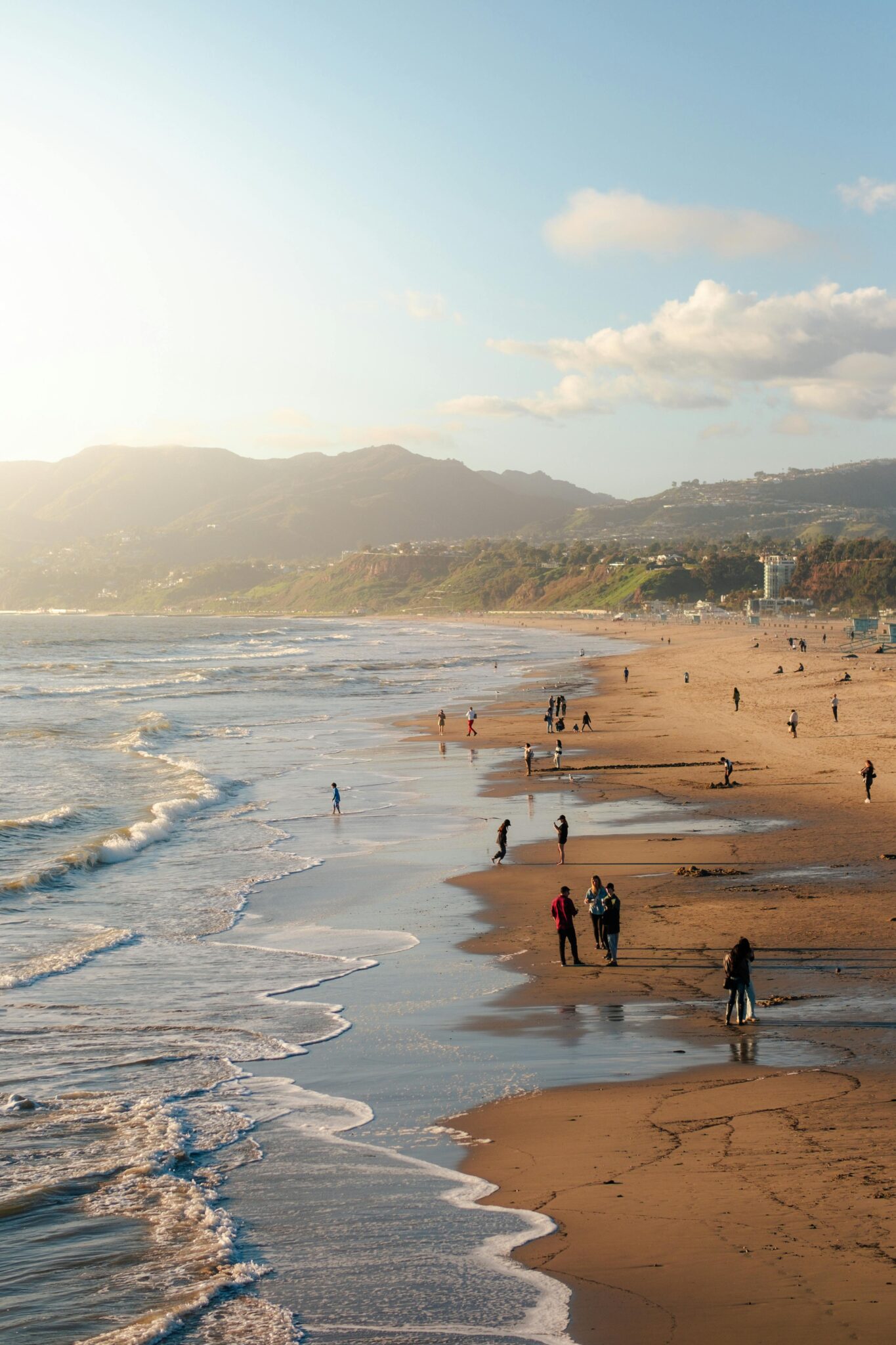 A serene sandy beach at Pacific Beach, California, with gentle waves lapping at the shore under a clear blue sky.