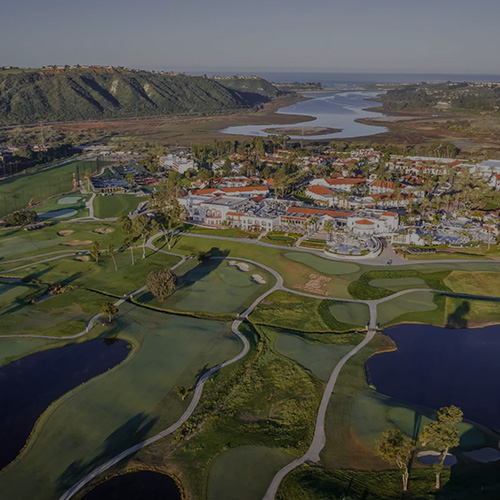 Aerial view of the golf course at the La Costa resort in Carlsbad, CA, showcasing lush greens and scenic landscapes.