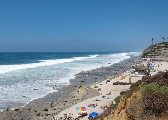 Families swimming and fishing at Moonlight State Beach in Encinitas San Diego. Discover homes for sale opportunities with the best real estate agents