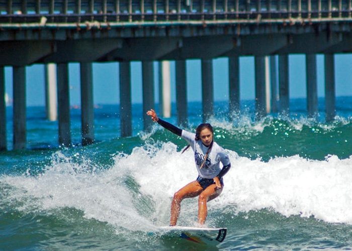 A woman gracefully rides a wave on a surfboard, displaying her skill and balance in the thrilling sport of surfing in Ocean Beach San Diego