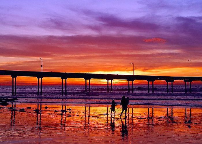 A couple strolling on the beach during sunset, enjoying the serene beauty of the moment at Ocean Beach San Diego