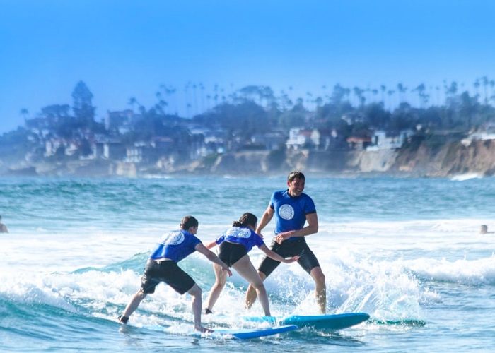 Friends surfing at Pacific Beach. Discover homes for sale opportunities in Mission Beach with the best real estate agents in San Diego